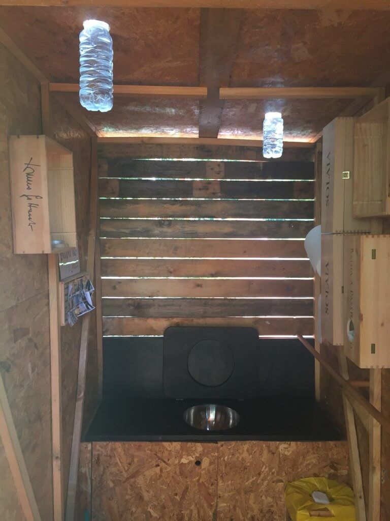 Outhouse that lights up in the dark with water and alge from bottles placed in the celing.